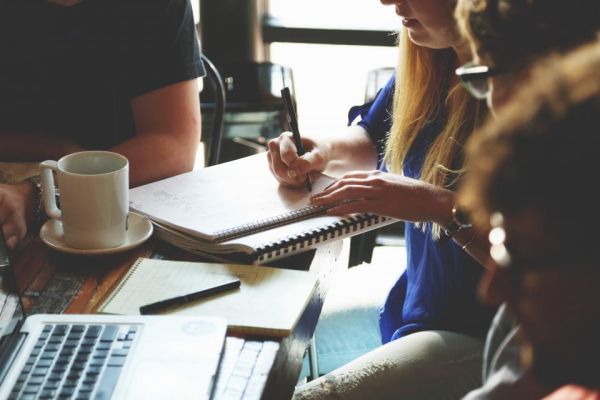 Teamoverleg met laptop en notitieblok aan tafel