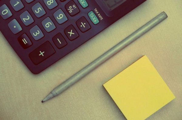 Rekenmachine met pen en notitieblok op een bureau