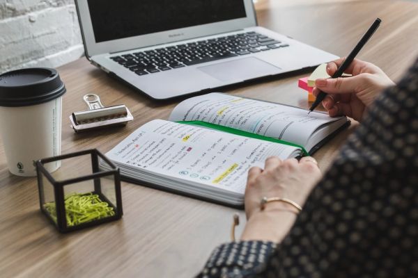 Tekstschrijver werkt met notitieboek en laptop aan websiteteksten