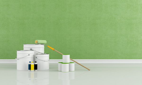 Verfblikken en verfroller voor een frisgeschilderde groene muur